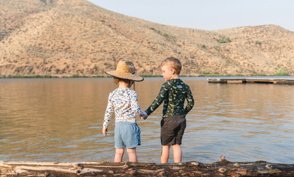 Two kids on the river bank holding hands